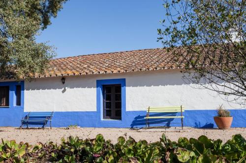 two benches in front of a blue and white building at Monte do Serrado De Baixo in Évora