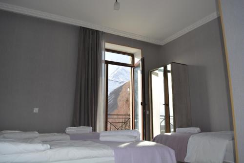 two beds in a room with a large window at Hotel Elegant in Kazbegi