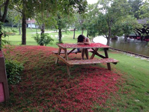 a woman sitting on a bench in a park at Flamingo Dailai - HQ villa in Ngọc Quang