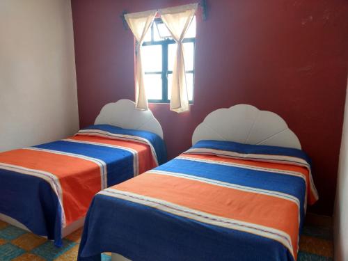 two beds in a room with a window at Hotel Hacienda Morales. in Guanajuato