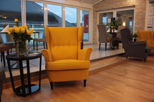 a yellow chair in a room with a table at Hotel Am Markt in Karlsruhe