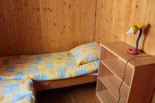 a bedroom with a bed with a lamp on a dresser at Domki " ELRINO " in Jastarnia