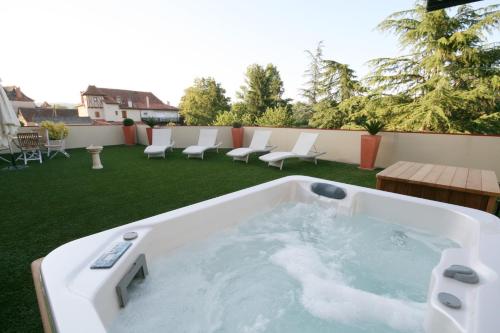a jacuzzi tub on a patio with chairs at Logis Auberge La Diege in Capdenac-Gare