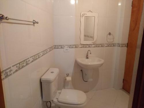 ein weißes Bad mit einem WC und einem Waschbecken in der Unterkunft Apartamento Campos do Jordão in Campos do Jordão