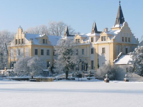 a large yellow building with snow on the ground at Schloss und Gut Liebenberg in Liebenberg