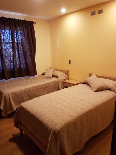 two beds in a hotel room with a window at Portal Austral in Puerto Montt