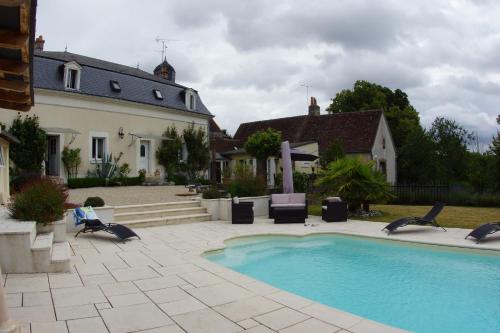 une piscine dans une cour avec des chaises et une maison dans l'établissement le petit nid, à Neuillé-le-Lierre