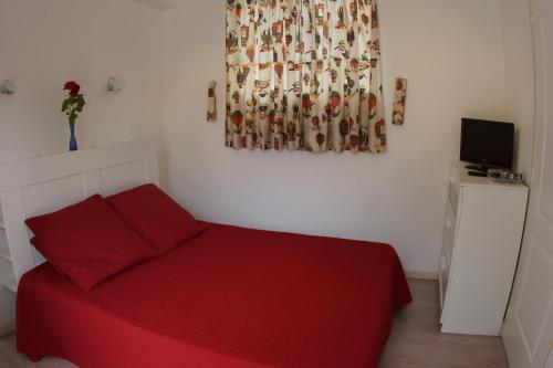 ein Schlafzimmer mit einem roten Bett und einem Gemälde an der Wand in der Unterkunft le petit nid in Neuillé-le-Lierre