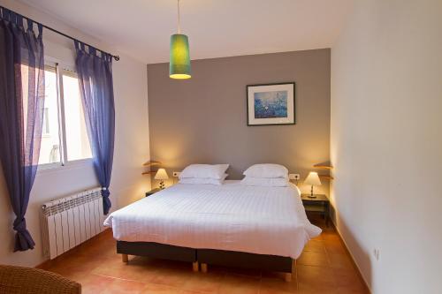 a bedroom with a white bed with two pillows at Finca el Rabilargo in Arroyomolinos de Montánchez