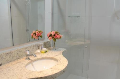 uma casa de banho com um lavatório e um chuveiro com flores em Unico Apart Hotel em Feira de Santana