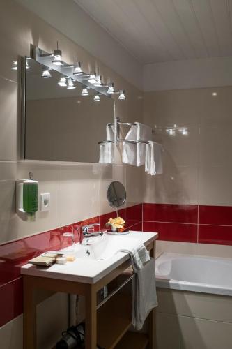 ein Badezimmer mit einem Waschbecken, einem Spiegel und einer Badewanne in der Unterkunft Hotel Restaurant La Paix in Le Nouvion-en-Thiérache