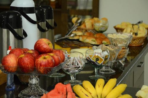 a buffet with apples and bananas and wine glasses at Hotel Flamboyant in Catalão