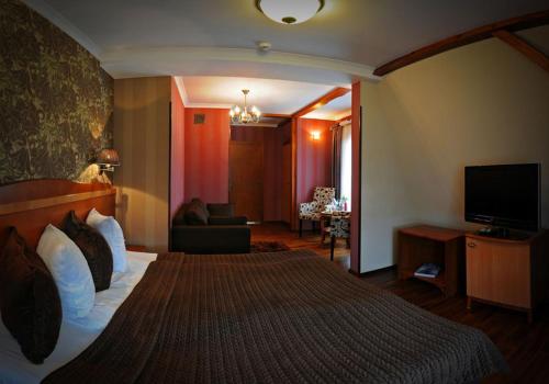 ein Hotelzimmer mit einem großen Bett und einem TV in der Unterkunft Villa Solankowa in Inowrocław