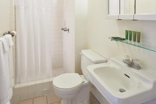 een witte badkamer met een toilet en een wastafel bij Pacific Marina Inn in Honolulu