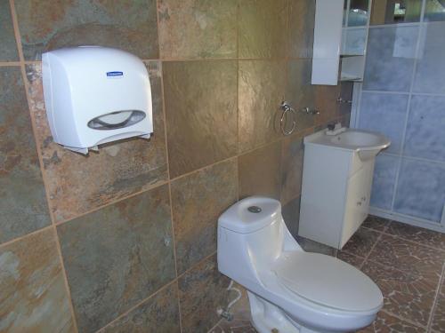 a bathroom with a toilet and a paper dispenser on the wall at Hostal Villas Mexico in San Juan del Sur