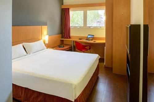 a bedroom with a bed and a desk with a laptop at ibis Belem Aeroporto in Belém