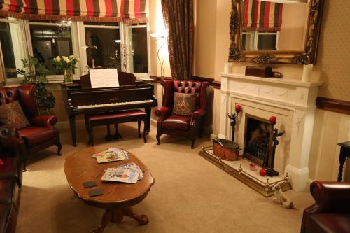 a living room with a fireplace and a piano at Woodlands in Windermere