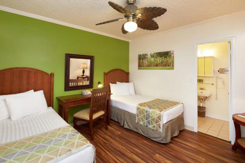a bedroom with two beds and a desk and a sink at Pacific Marina Inn Airport in Honolulu