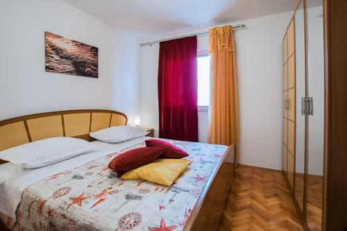 1 dormitorio con cama con almohadas y ventana en Apartman Antea, en Trogir