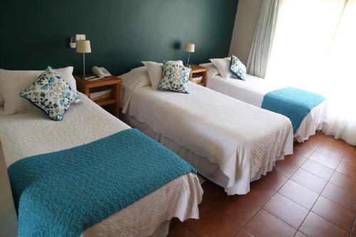 a room with three beds with blue and white at Hotel Altos de Tuqui in Ovalle