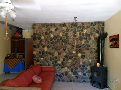 a living room with a red couch in front of a stone wall at Jardin de Estrellas in San Marcos Sierras