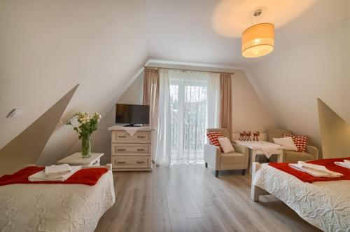 a attic bedroom with two beds and a living room at Dom Wypocz Pod Litwinką Apartamenty in Białka Tatrzańska