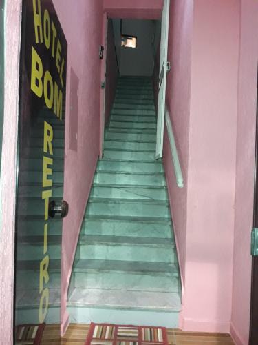 un tramo de escaleras en una habitación rosa con puerta en Hotel bom retiro en São Paulo