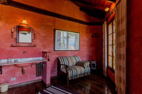 a red room with a chair and a mirror at Feiticeira Guesthouse in Ilhabela