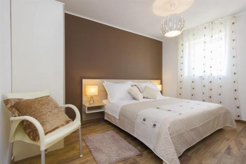 a bedroom with a white bed and a chair at Dalmatian stone Villa Burica in Vinišće