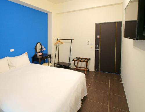 台東市的住宿－輕旅村-陽光輕旅（電梯民宿），卧室配有白色的床和蓝色的墙壁