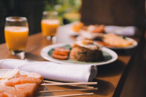 een tafel met borden eten en glazen sinaasappelsap bij Ume Sri Villas Ubud in Ubud