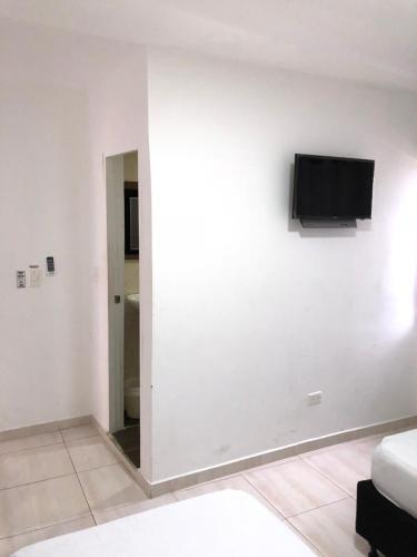 a living room with a tv on a white wall at Posada Doña Rosa in San Andrés