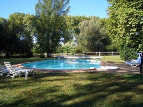 una piscina en un patio con 2 sillas de césped en Le Platane, en Lafrançaise