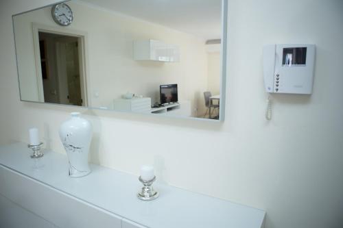 een witte badkamer met een spiegel en een vaas op een wastafel bij Apartamento Ideal 2 in Lissabon