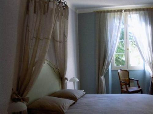a bedroom with a bed with curtains and a window at Le Platane in Lafrançaise
