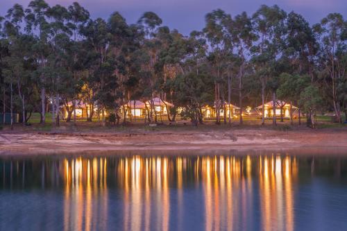 uma vista do alojamento de turismo selvagem a partir da água à noite em Olio Bello Lakeside Glamping em Cowaramup