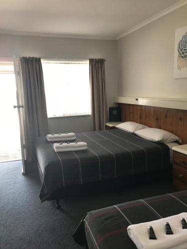 Habitación de hotel con 2 camas y ventana en Glenrowan Kelly Country Motel en Glenrowan