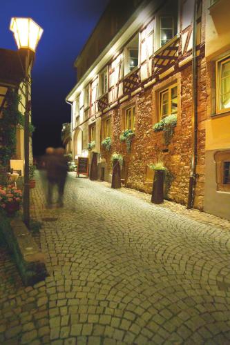 a person walking down a cobblestone street at night at Die Reichsstadt - Hotel Spa und Restaurant in Gengenbach