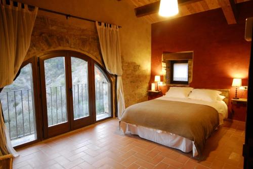 a bedroom with a large bed and large windows at O Chardinet d'a Formiga in Aínsa