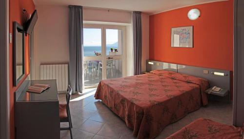 ポルトフェッラーイオにあるHotel Villa Ombrosaのベッド付きのホテルルームで、海の景色を望めます。