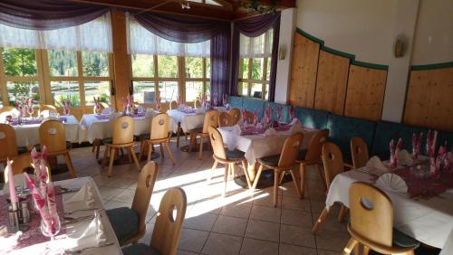 un comedor con mesas, sillas y ventanas en Pension Siegelbrunn B&B, en Mallnitz