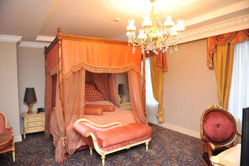 a bedroom with a canopy bed and a chandelier at Hotel Intourist Palace Batumi in Batumi