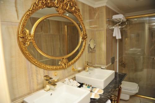a bathroom with a gold mirror and a sink at Hotel Intourist Palace Batumi in Batumi