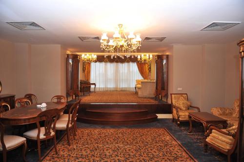 a living room with a chandelier and a table and chairs at Hotel Intourist Palace Batumi in Batumi