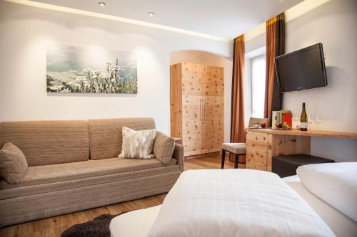 a hotel room with a couch and a tv at Gasthof zum goldenen Löwen in Nauders