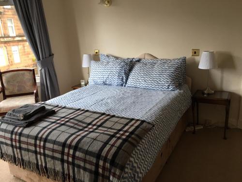 um quarto com uma cama com um cobertor xadrez e uma janela em Charles's Street em Largs