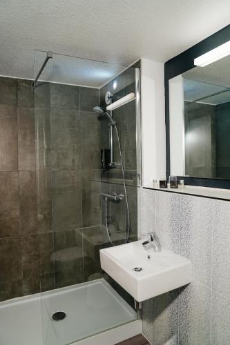 a bathroom with a shower and a sink and a mirror at Kyriad Lille - Roncq in Roncq