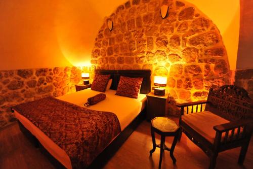 1 dormitorio con cama y pared de piedra en Kadim Hotel, en Mardin