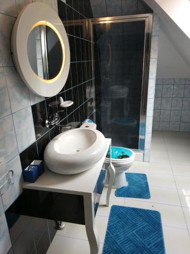 a bathroom with a sink and a toilet with blue rugs at Pałac Ogrodowa in Tarnowskie Góry