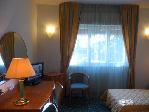 a hotel room with a bed and a desk and a window at Hotel Cristallo in Udine